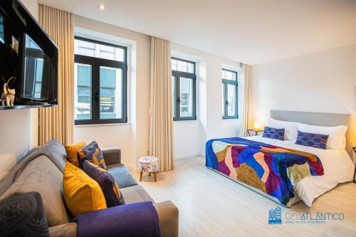 een slaapkamer met een bed en een bank bij Porto Formosa Central Lofts in Porto