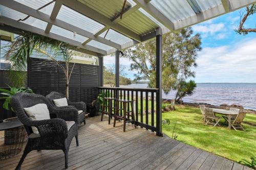 a deck with chairs and a table and the ocean at The Waterfront House - Pet Friendly - Absolute Waterfront in Erowal Bay