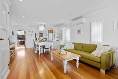 a living room with a green couch and a table at The Waterfront House - Pet Friendly - Absolute Waterfront in Erowal Bay