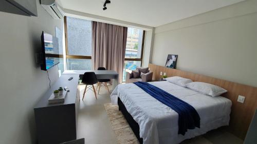 a bedroom with a bed and a desk and a window at Flat Novo em Boa Viagem - Rooftop 470 in Recife