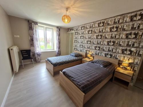 a bedroom with two beds and a wall with pictures at Grand gîte tout équipé à la ferme, idéal pour familles et amis, avec terrasse et proche de loisirs - FR-1-584-295 in Lironville