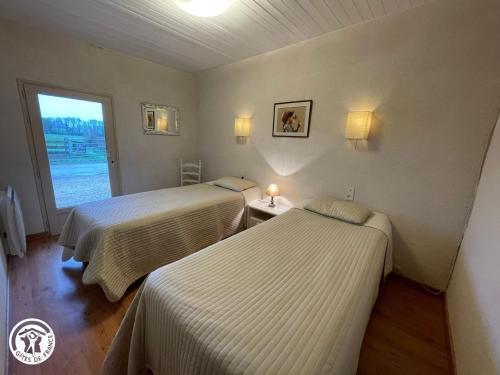 two beds in a room with a window at Gîte charmant à la campagne avec terrasse, proche du Puy du Fou et de la rivière Sèvre - FR-1-426-249 in Sevremont