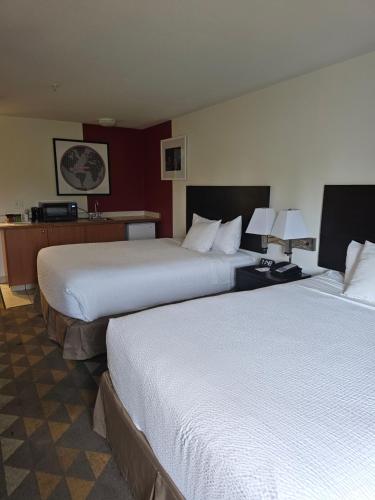 a hotel room with two beds and a desk at Ramada by Wyndham SeaTac Airport in SeaTac