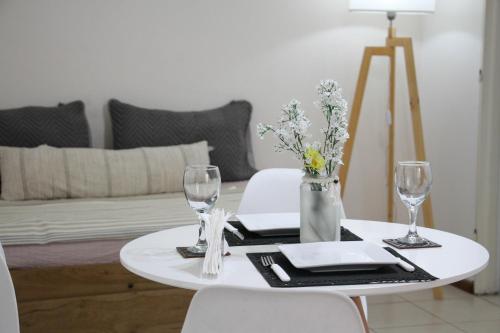 una mesa blanca con 2 sillas y una mesa con copas de vino en La Quinta departamento en Mendoza