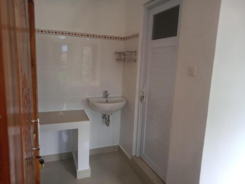 Baño blanco con lavabo y puerta en Chiinta House, en Ubud