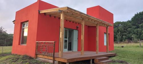 a red house with a deck in a field at Casa Rose Chapadmalal in Mar del Plata