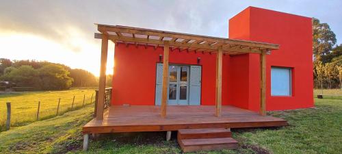 a red house with a wooden deck in a field at Casa Rose Chapadmalal in Mar del Plata