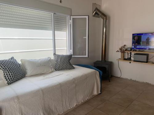 1 dormitorio con 1 cama, ventana y TV en Casa Monte hermoso a media cuadra Del Mar en Monte Hermoso