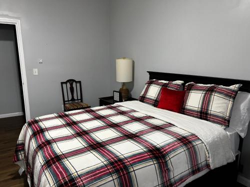 1 dormitorio con 1 cama con manta a cuadros y almohadas rojas en Country Club, en Wadley