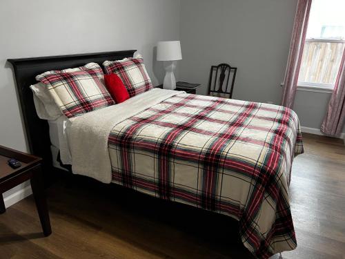 1 cama con almohadas rojas y manta a cuadros en Country Club, en Wadley