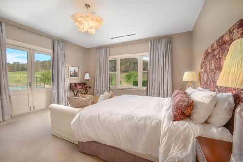 una camera da letto con un grande letto bianco e finestre di Carinya, Berrima, Southern Highlands a Berrima