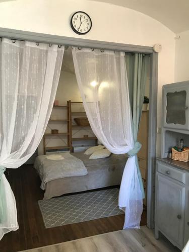 1 dormitorio con 1 cama con cortinas y reloj en Studio couple cosy en Mont-Dauphin