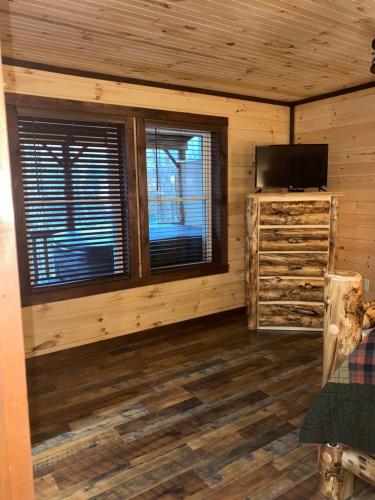 uma cabina de madeira com uma televisão e uma janela em Lakeside Cabin Hot tub close to Ark Encounter em Corinth