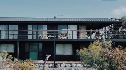 a house with a balcony with chairs on it at Dusk Coffin Bay in Coffin Bay