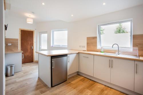 an empty kitchen with white cabinets and a sink at Mike's 3-bedroom Countryside Cottage in Alness