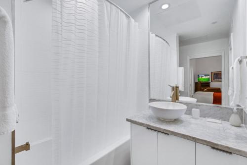 One Lux Stay HWH Downtown Los Angeles في لوس أنجلوس: حمام أبيض مع حوض ومرآة