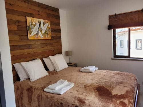 a bedroom with a large bed with two towels on it at Zenhouse in São Martinho do Porto