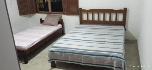 1 dormitorio con 2 camas y ventana en Casa prática e completa próxima de tudo en Ubatuba