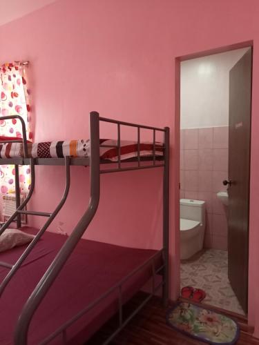 a bunk bed in a pink room with a bathroom at Josephine's Home Donsol Sorsogon in Donsol