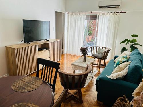 sala de estar con sofá azul y TV en Departamento 3 ambientes con patio, terraza y parrila en Buenos Aires