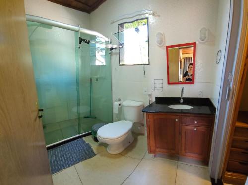 a bathroom with a toilet and a glass shower at Apartamento Buziano in Búzios