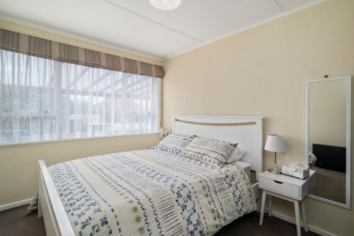 a white bedroom with a bed and a window at Whare 35 - Rotorua Holiday Home in Rotorua