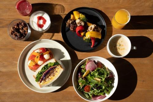 un tavolo con piatti di cibo e ciotole di insalata di Hotel Anteroom Kyoto a Kyoto