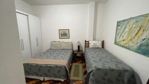 a small room with two beds and a painting at Copacabana, confortável apto de 2 quartos, quadra da praia in Rio de Janeiro