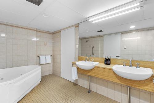 a bathroom with two sinks and a tub and a mirror at Comfort Hotel Adelaide Meridien in Adelaide