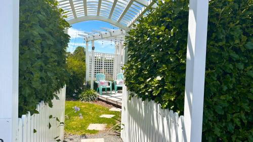 an archway in a garden with a white fence at Rustling Oaks NZ Tropical Tiny House in Tamahere