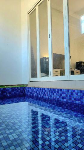 a swimming pool with blue tiled floors and a window at MG'S Villa in Batu