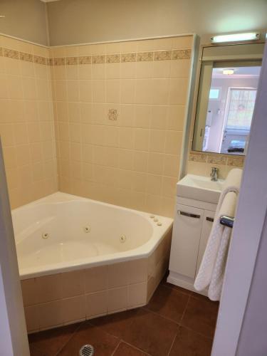 a bathroom with a bath tub and a sink at Ferns Miners Rest Motel in Mount Morgan