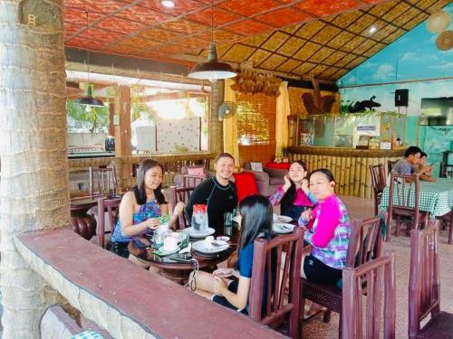 a group of people sitting at a table in a restaurant at Coco Grove Nature Resort in Himensulan