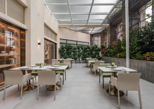 un restaurante con mesas, sillas y plantas en The Skytel Hotel Shenzhen Central Park, en Shenzhen