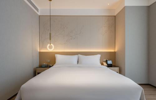 a bedroom with a large white bed and a wall at The Skytel Hotel Shenzhen Central Park in Shenzhen