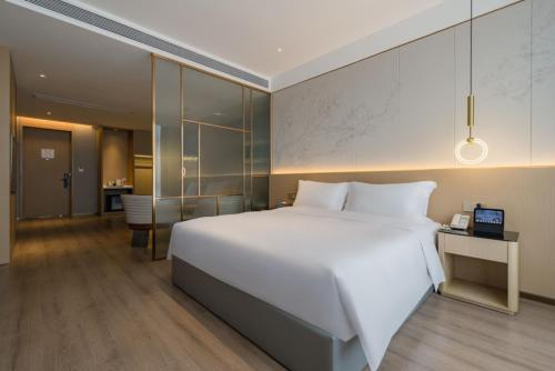 a bedroom with a large white bed and a desk at The Skytel Hotel Shenzhen Central Park in Shenzhen