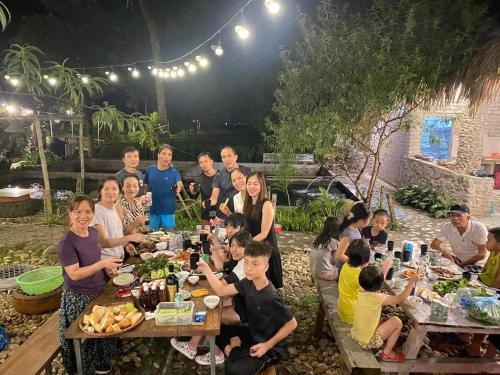 Eine Gruppe von Menschen, die an Tischen sitzen und Essen essen. in der Unterkunft Dao's House Hoang Nong in Lá Cam