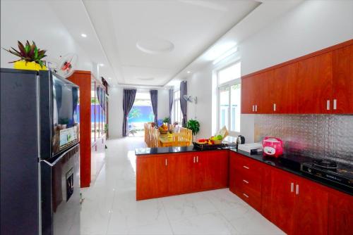 a kitchen with wooden cabinets and a tv in it at The Luka Pool Villa Vung Tau in Vung Tau