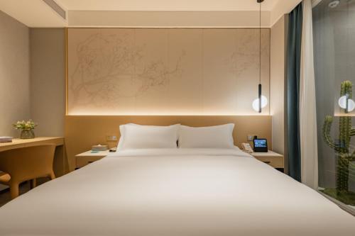 a bedroom with a large white bed and two desks at The Skytel Hotel Shenzhen Central Park in Shenzhen