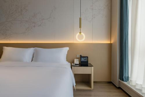 a bedroom with a bed and a table with a clock at The Skytel Hotel Shenzhen Central Park in Shenzhen