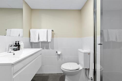 Baño blanco con aseo y lavamanos en Econo Lodge North Adelaide en Adelaida