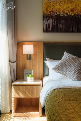 a bedroom with a bed and a night stand with a lamp at Son&Henry Zenity District 1 in Ho Chi Minh City