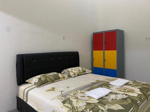 a bed with a black headboard and a colorful cabinet at The 8 House – Surabaya City Center in Surabaya