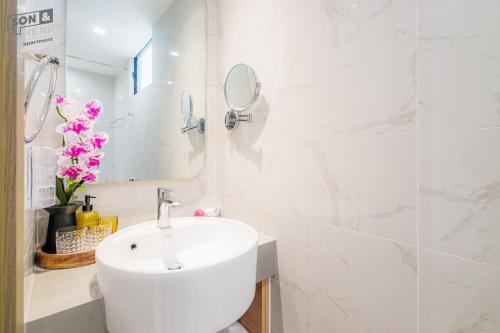 a white bathroom with a sink and a mirror at Son&Henry Zenity District 1 in Ho Chi Minh City