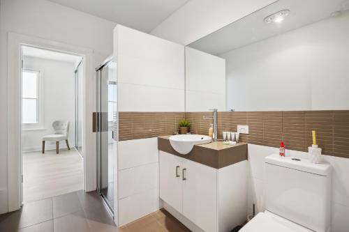 a white bathroom with a sink and a toilet at Swainson at Del Monte in Henley Beach South