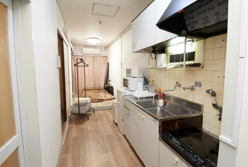 een kleine keuken met een wastafel en een fornuis bij DM402 観光名所とナイトライフの拠点となる魅力的な宿泊施設 in Osaka