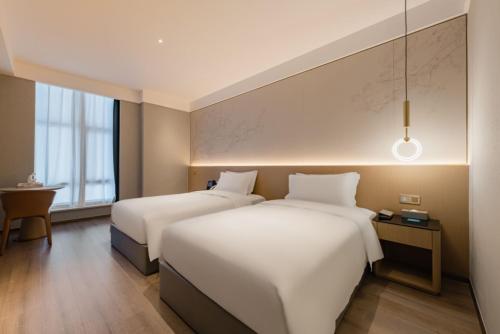two beds in a hotel room with at The Skytel Hotel Shenzhen Central Park in Shenzhen