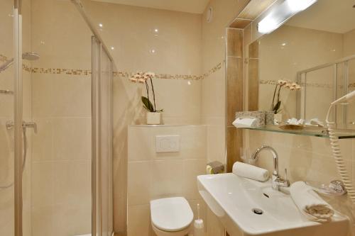 een badkamer met een wastafel, een douche en een toilet bij Hotel Garni Jennewein in Mayrhofen