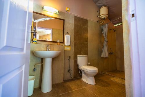 a bathroom with a sink and a toilet and a mirror at Banyan By The Ganges in Devaprayāg