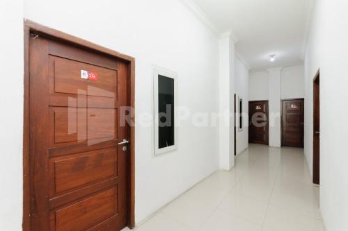 a corridor with a wooden door in a building at RedDoorz at Wisma Nabila Syariah near Masjid Raya Baiturrahman Banda Aceh in Banda Aceh